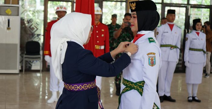 Way Kanan – Suasana tegang menyelimuti Gedung Pusiban Pemkab Way Kanan, Sabtu (16/08/2025). Puluhan pemuda-pemudi yang terpilih jadi Pasukan Pengibar Bendera Pusaka (Paskibraka) Tahun 2025 resmi dikukuhkan. Bupati Way Kanan, Ayu Asalasiyah, S.Ked., menegaskan keras, tugas mulia itu bukan sekadar seremoni. “Ini awal tanggung jawab besar. Jangan pernah main-main dengan Merah Putih,” ujarnya. Ia menyorot setiap tetes keringat para anggota Paskibraka selama pelatihan sebagai bukti kesungguhan mereka. “Kalian adalah duta generasi muda Way Kanan. Jangan hanya gagah saat mengibarkan bendera, tapi jadilah teladan di tengah masyarakat. Integritas, disiplin, dan cinta tanah air harus nyata,” tegasnya. Bupati juga mengingatkan, tanggung jawab itu tidak berhenti pada 17 Agustus. “Semangat dan kebersamaan yang kalian pupuk di pelatihan harus dibawa ke kehidupan sehari-hari. Jangan sekali-kali nodai amanah ini,” katanya dengan suara bergetar. Dalam acara yang dijaga ketat itu, hadir pula Forkopimda, Sekda Machiavelli Herman Tarmizi, Ketua Dharma Wanita Dhelya Machiavelli, para pejabat Pemkab hingga perwakilan instansi vertikal. Semua saksi bisu, saat sumpah pengukuhan menggema—menandai awal tanggung jawab berat di pundak para pengibar bendera Merah Putih.